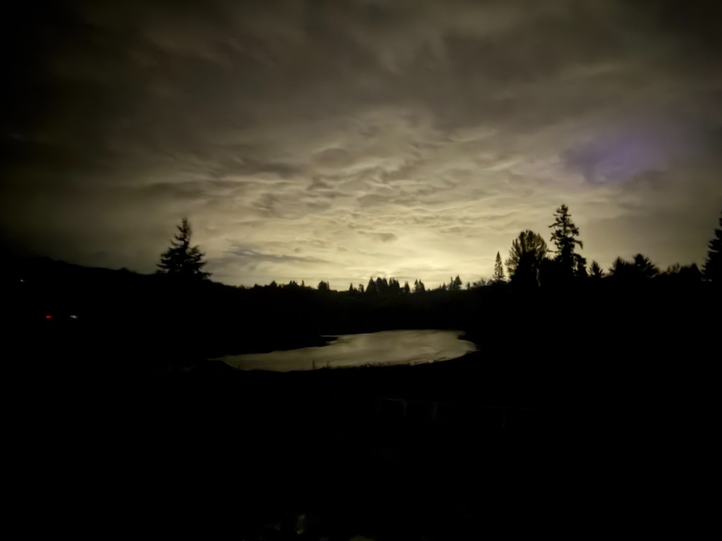 Dramatic evening sky and dusk light over Lewis River with silhouetted evergreen trees at Lewis River Estate near Portland Oregon